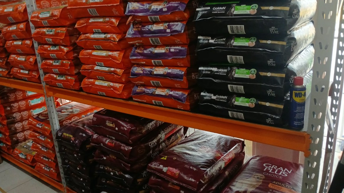 Prateleira da loja com sacos de ração de 15 kg de várias marcas empilhados